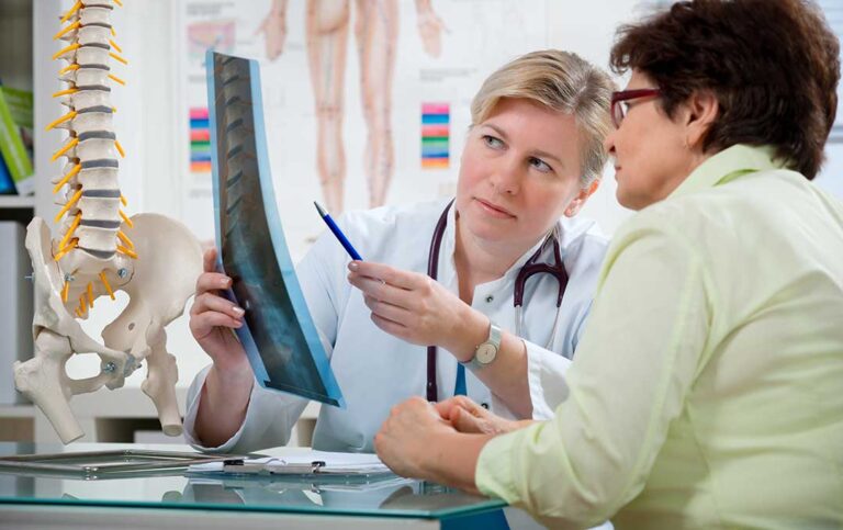 A chiropractor demonstrating a gentle back adjustment to a middle-aged patient in a health clinic setting.