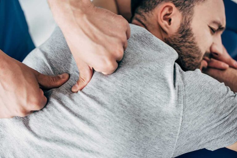 A person gently stretching their shoulder with visible focus on the shoulder area.